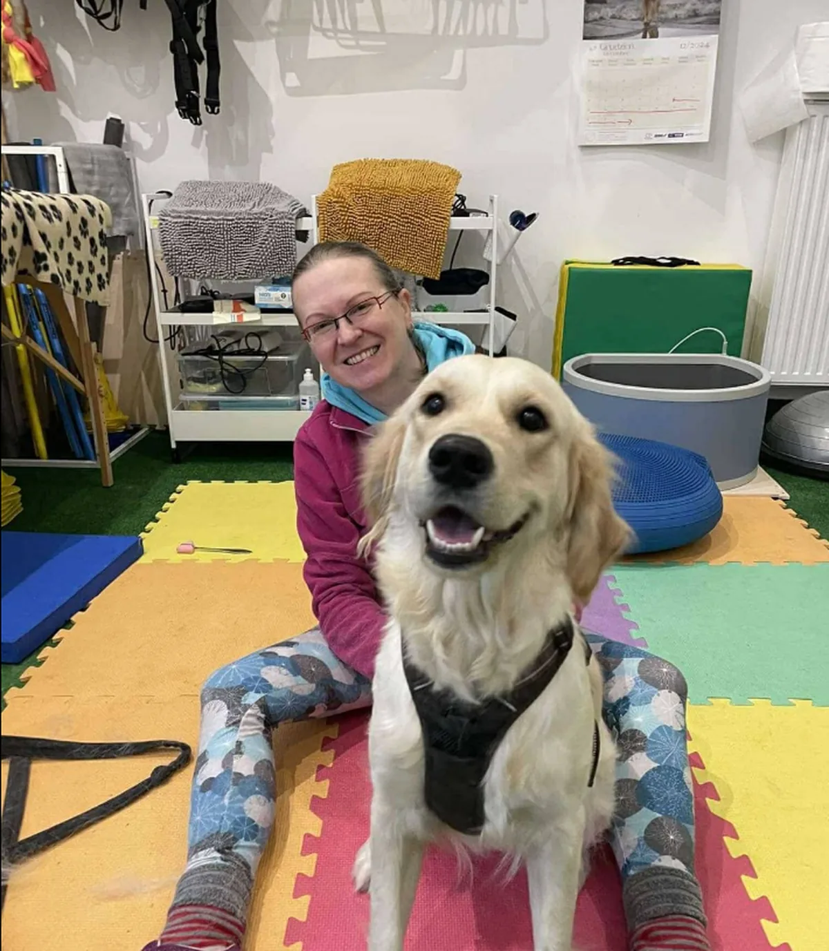 Fizjoterapeutka z zadowolonym golden retrieverem po sesji